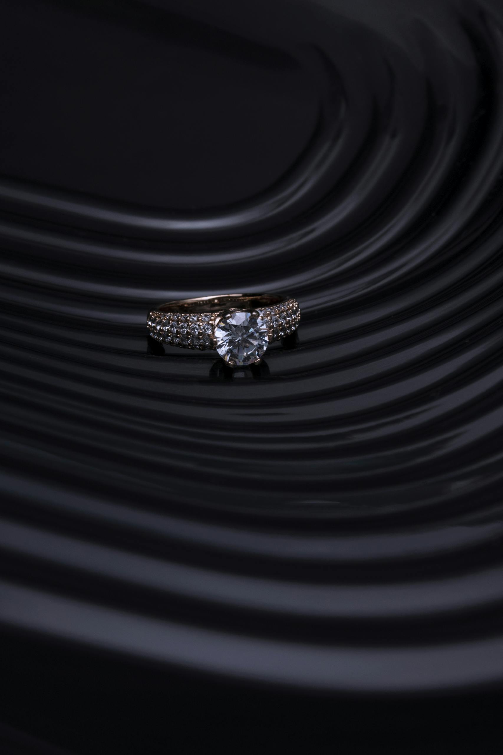 Close-up of a diamond ring with a dark, wavy background creating a luxurious and elegant atmosphere.