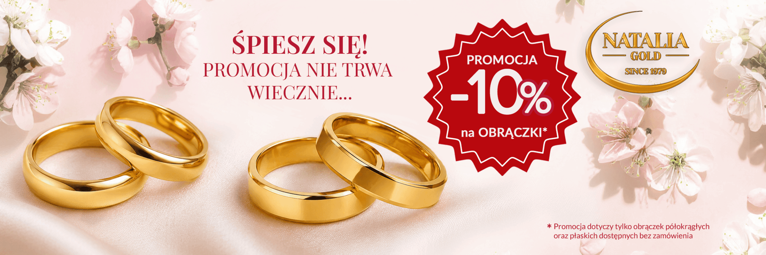 Baner promocyjny marki Natalia Gold prezentujący dwie pary złotych obrączek ślubnych (klasyczne półokrągłe oraz nowoczesne płaskie) na jasnoróżowym, satynowym tle ozdobionym gałązkami kwitnącej wiśni. Na banerze znajdują się napisy: „ŚPIESZ SIĘ! PROMOCJA NIE TRWA WIECZNIE…” oraz duża, czerwona pieczęć z hasłem „PROMOCJA -10% na OBRĄCZKI*”. W prawym górnym rogu widoczne jest złote logo „NATALIA GOLD SINCE 1979”. U dołu ekranu umieszczono dopisek małym drukiem: „* Promocja dotyczy tylko obrączek półokrągłych oraz płaskich dostępnych bez zamówienia”.